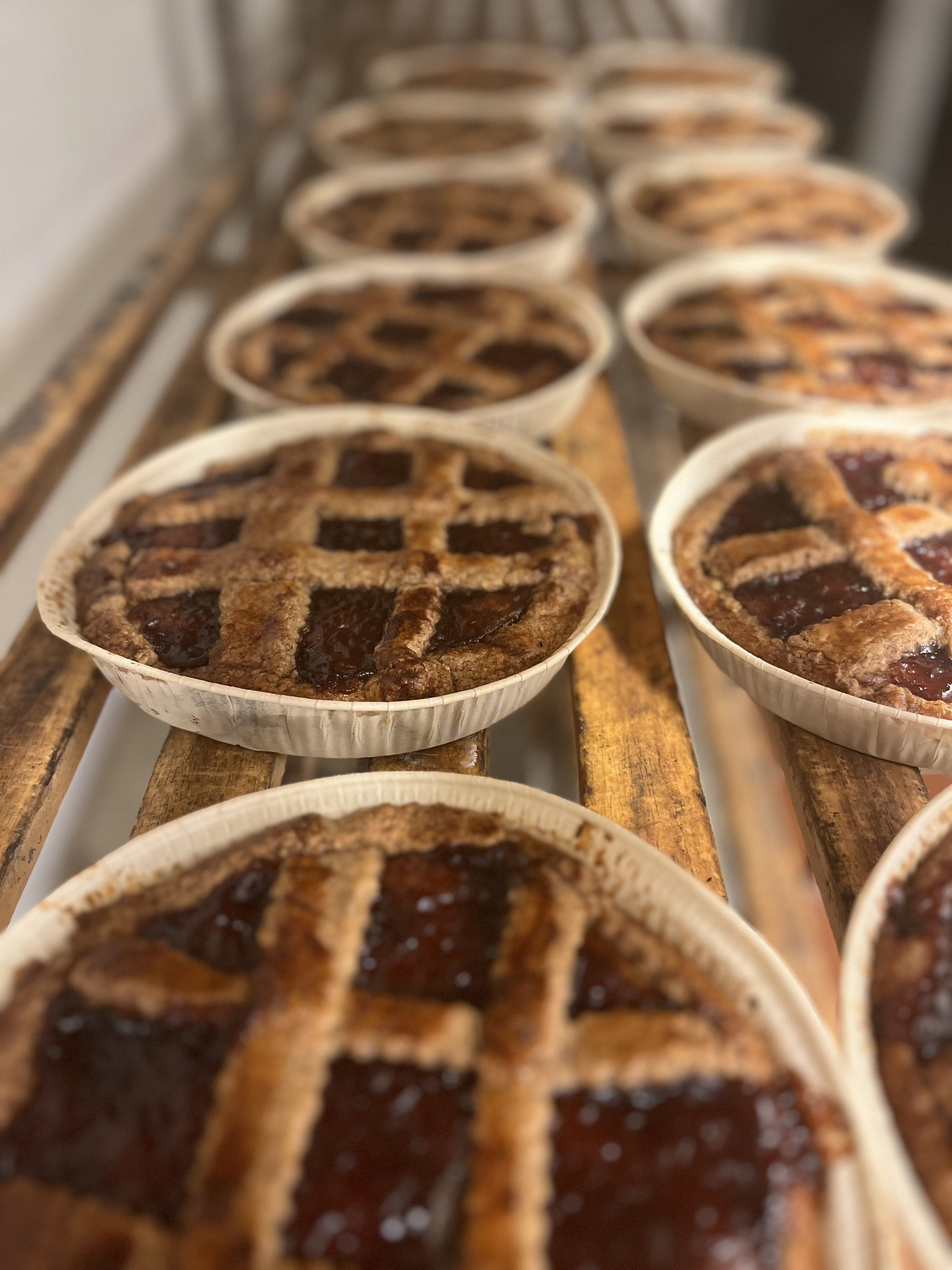 Marmeladentaler mit Gitter aus Mürbeteig auf einer Holzbank