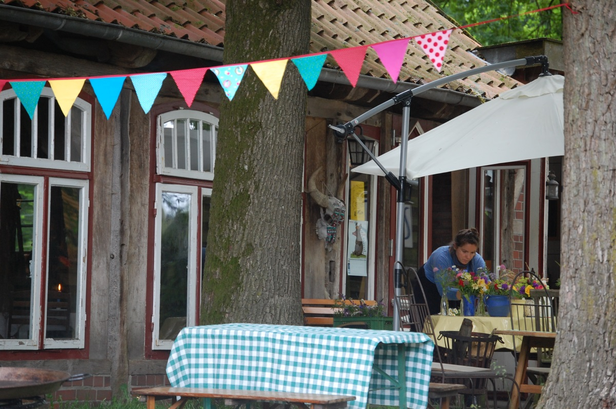 Hoffest mit Wimpelkette zwischen den Bäumen, gedeckte Tische unter dem Sonnenschirm