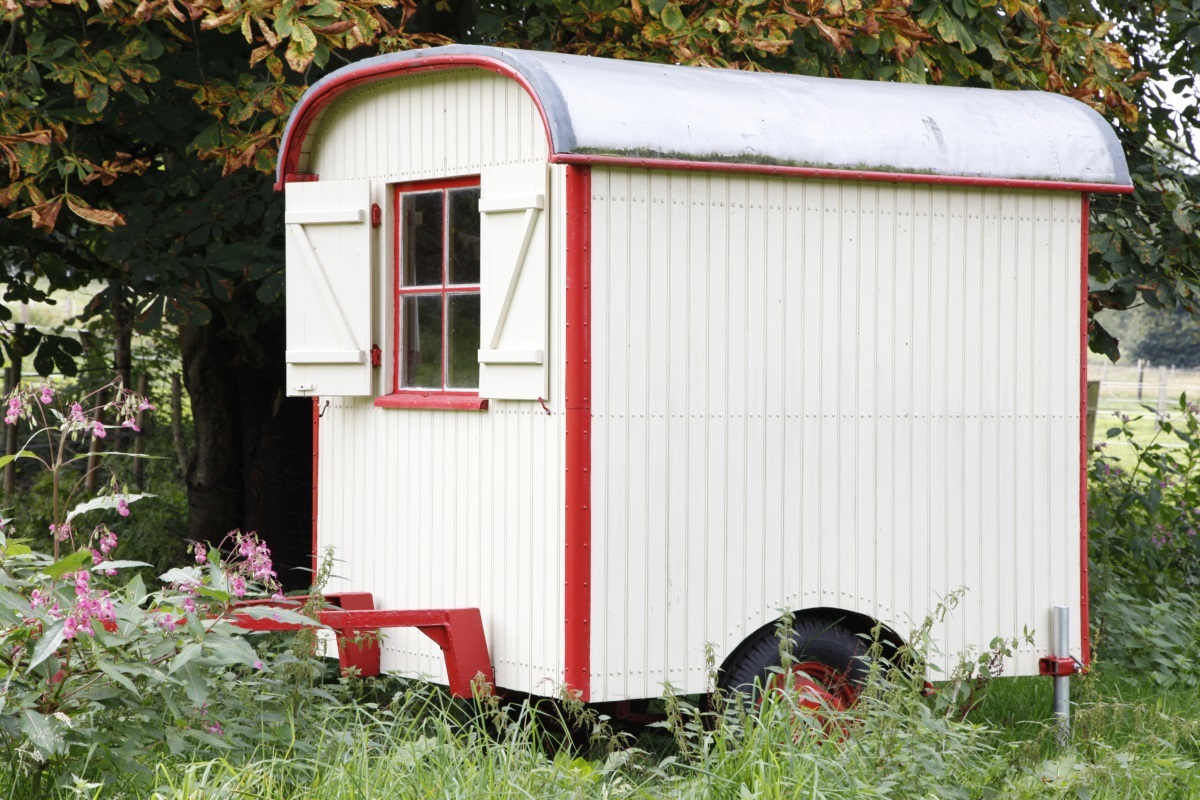 Übernachten im Zirkuswagen – weiß-roter Wagen zwischen Bäumen